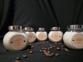 Handmade aromatic candles promoting calm and wellness, arranged on a dark surface with coffee beans, featuring unique fragrances.